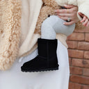 Close-up of BEARPAW Toddler Elle Zipper Boot in Black worn on foot with casual cold-weather styling for kids.