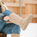 Close-up of BEARPAW Women's Elle Tall Boot in Mushroom worn on foot as part of a casual fall and winter outfit.