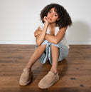 Model wearing Bearpaw suede clogs with decorative charms, styled for a cozy and casual everyday look