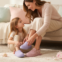 Mother and young daughter wearing pastel Bearpaw slippers in a cozy home setting, surrounded by soft decor and flowers, celebrating Mother’s Day with a warm and loving atmosphere.