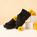 Black suede Bearpaw Sail mule lifestyle image with floral styling and platform sole, modern casual women’s footwear