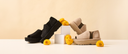 Bearpaw platform sandals in black and beige displayed on a minimal set with yellow flowers, highlighting summer style and comfort